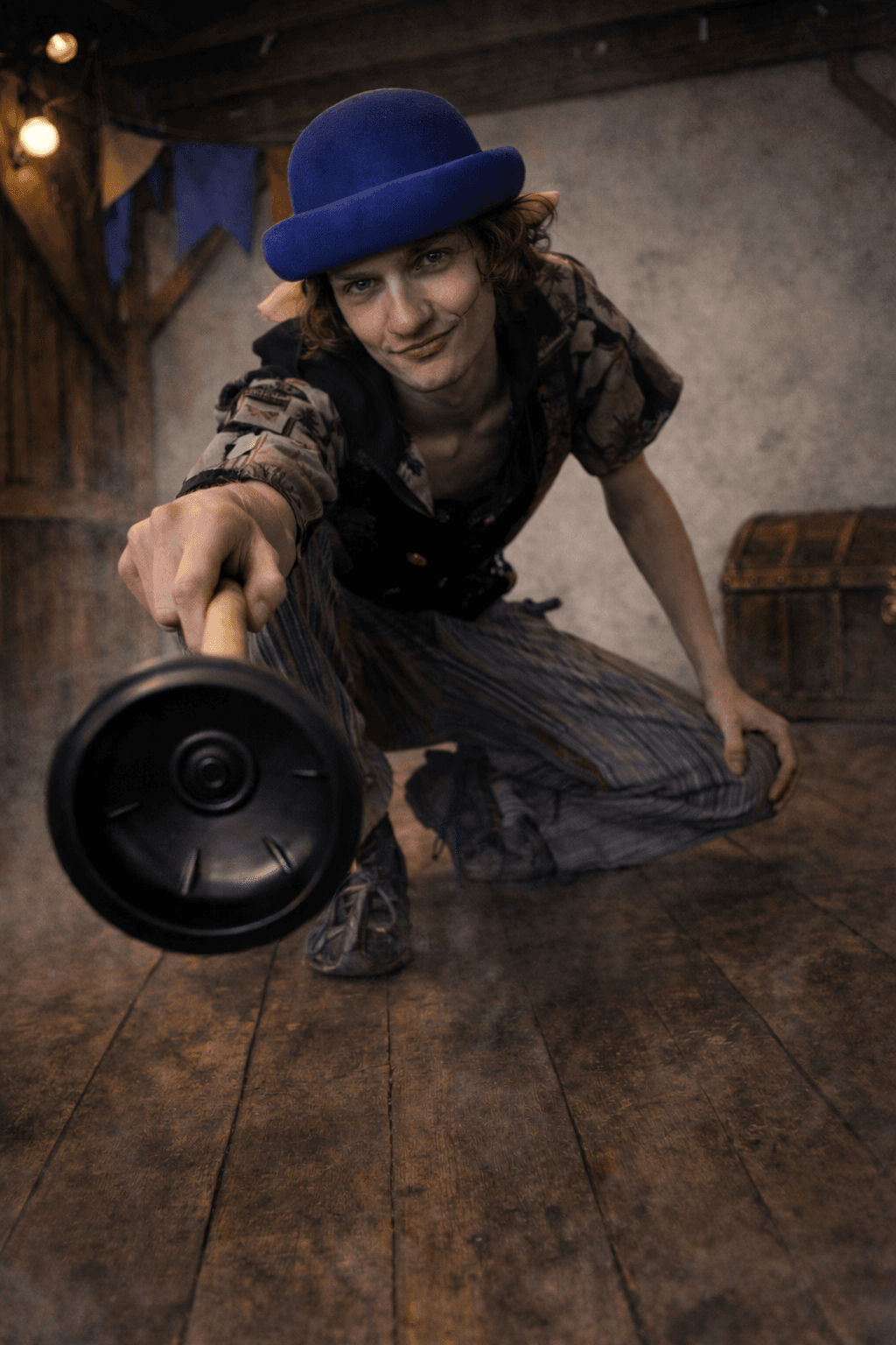 Stu of the Loo in character — a sewer rat with a blue bowler hat, crouching on a wooden stage with plunger in hand